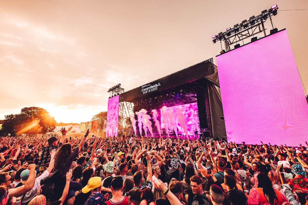 The Creamfields South stage with pink lights and smoke and a crowd of people in front.