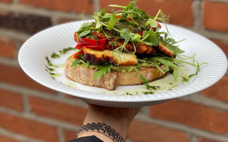 Sourdough toast topped with avocado, grilled halloumi and pesto.