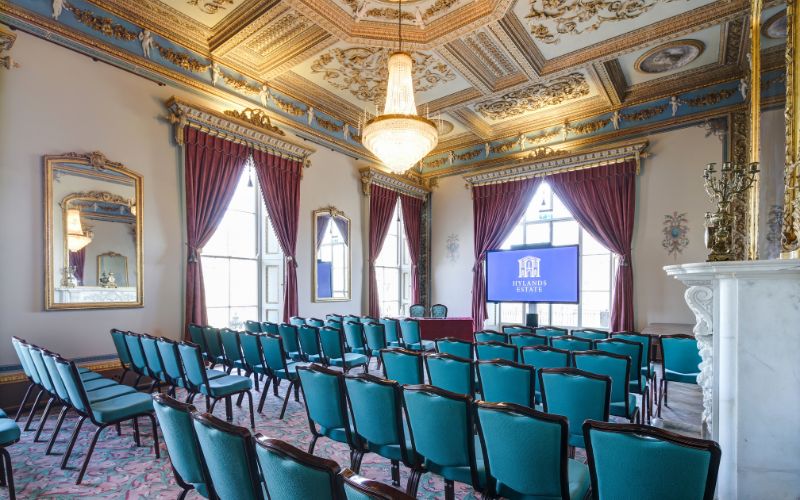 The Drawing Room set up for a corporate event with rows of chairs and a large screen up front.