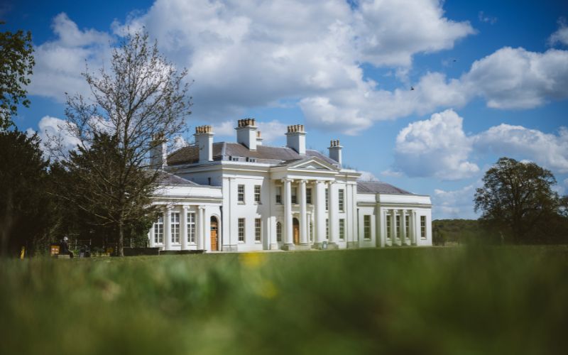 The exterior of Hylands House with the green front lawn in the foreground.