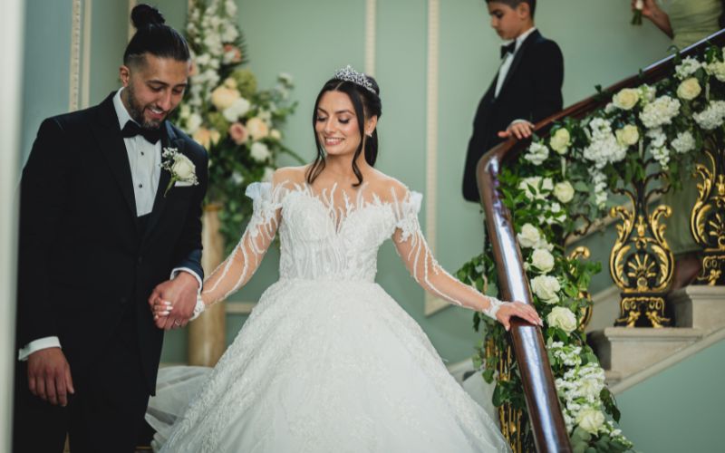 A bride and groom walking down the grand staircase.