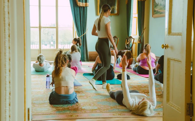 A group of people doing yoga in the Drawing Room of Hylands House.